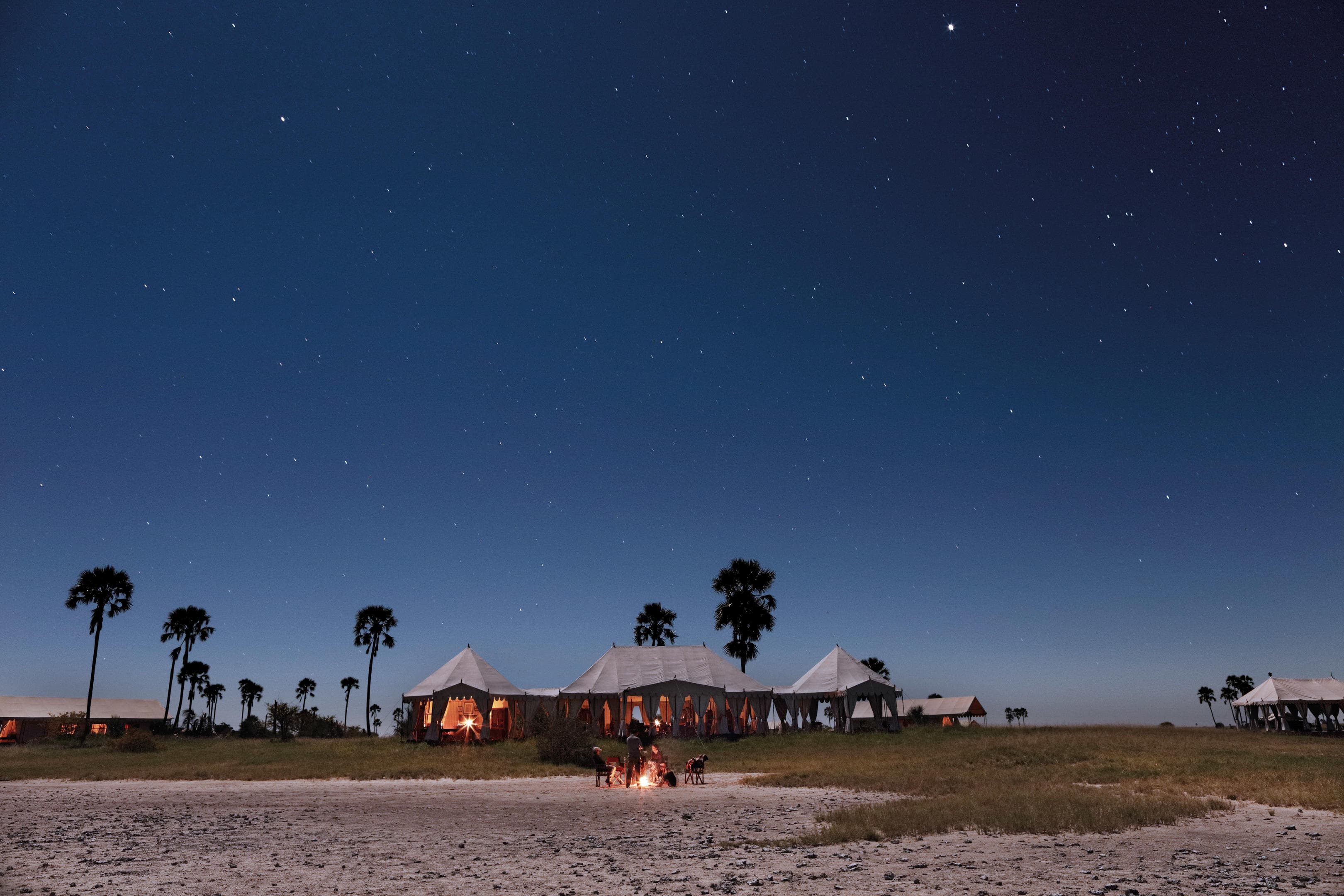 Travelers camping in the Iranian desert at sunset with campfire